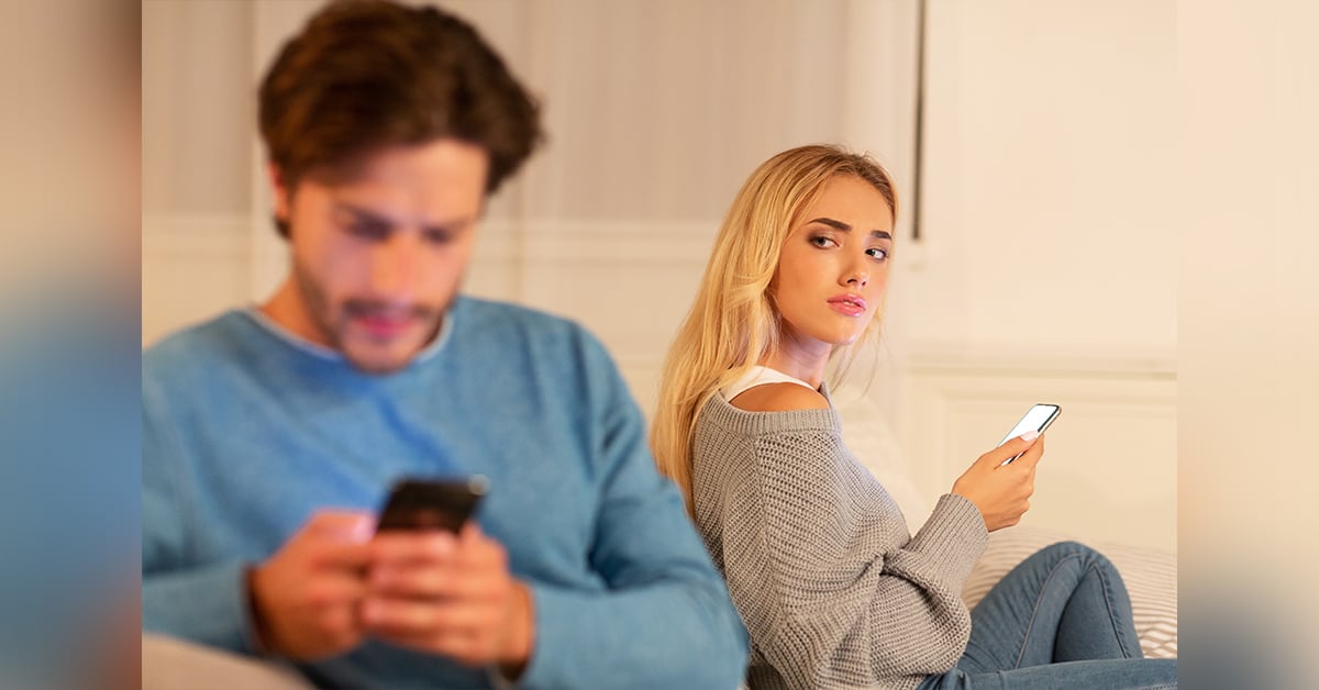 Man texting while woman looks on suspiciously.